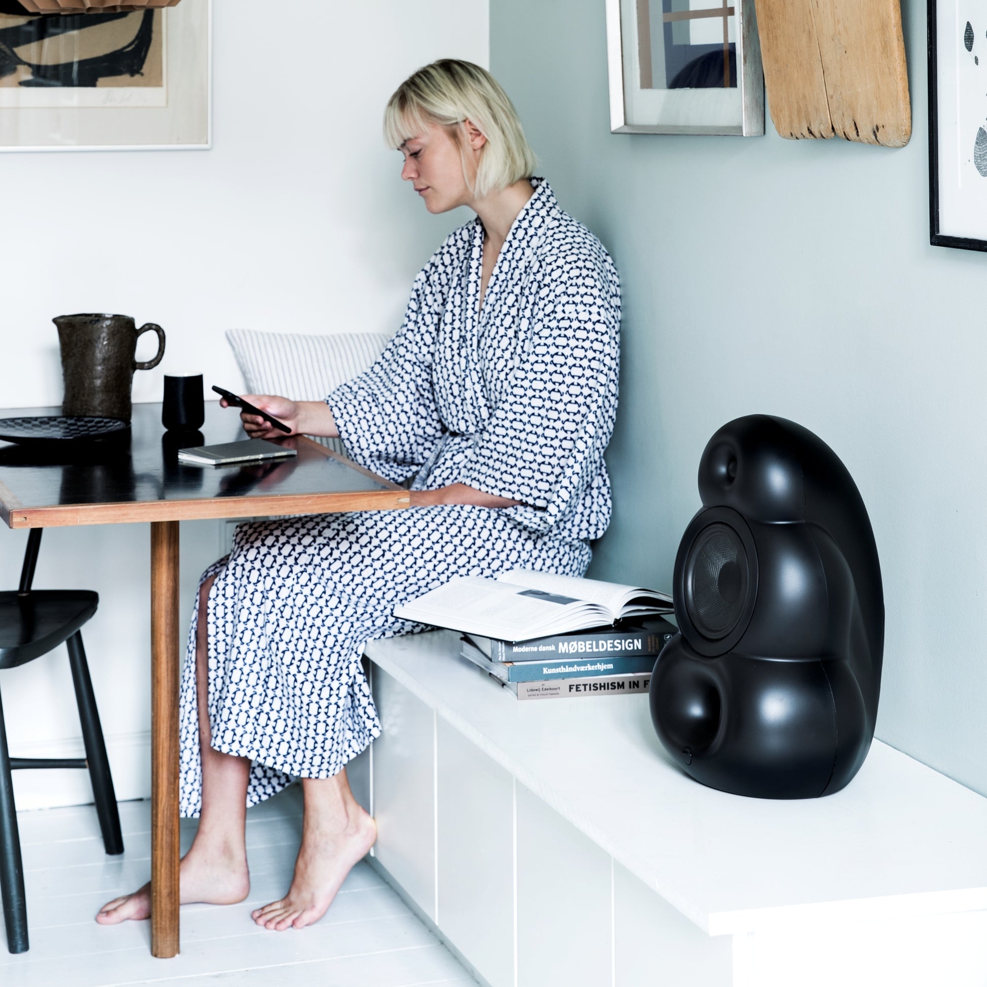 Scandyna BGP black matte hifi loudspeaker placed in kitchen with girl looking at her mobilephone