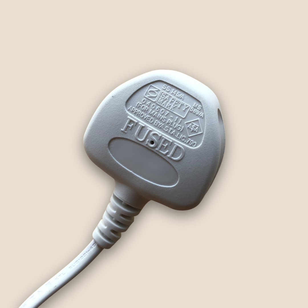 White electrical inlet power UK plug with 'FUSED' label on a beige background